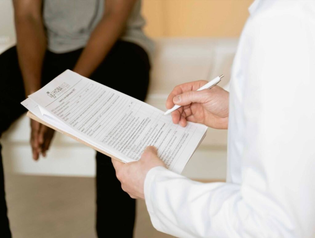 Finasteride y los efectos sexuales: qué dice realmente la evidencia Dermatólogo con bata blanca tomando notas en la historia clínica durante una consulta sobre el tratamiento con finasteride para la alopecia androgenética